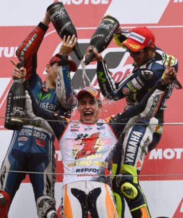 Márquez ganó su segundo mundial en MotoGP (cuarto mundial en total) en el Gran Premio de Japón. En la imagen, Jorge Lorenzo y Valentino Rossi mojan a Marc Márquez en el podio tras proclamarse campeón de MotoGP.