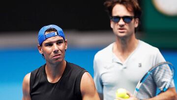 El tenista español Rafael Nadal (i) entrena en compañía de su entrenador Carlos Moya (d), en la pista Rod Laver Arena.
