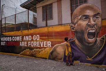 VALENZUELA, PHILIPPINES - JANUARY 28: A child stands next to a mural of former NBA star Kobe Bryant outside the "House of Kobe" basketball court on January 28, 2020 in Valenzuela, Metro Manila, Philippines.