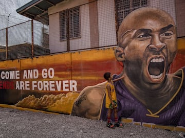 VALENZUELA, PHILIPPINES - JANUARY 28: A child stands next to a mural of former NBA star Kobe Bryant outside the "House of Kobe" basketball court on January 28, 2020 in Valenzuela, Metro Manila, Philippines.