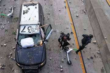 Dos agentes de la Patrulla de Carreteras de California intentan esquivar piedras lanzadas cerca del centro de detención metropolitano del centro de Los Ángeles.