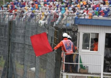 A race marshall waves a red flag to signal the race to be stopped due to heavy rain at the Formula One Japanese Grand Prix in Suzuka on October 5, 2014. AFP PHOTO/ TOSHIFUMI KITAMURA