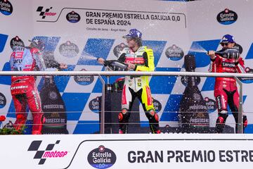 Los pilotos italianos Marco Bezzecchi y Pecco Bagnaia rocían con champán al piloto español en el pod¡o. 