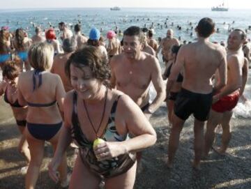 Decenas de ciudadanos participaron este mediodía en el tradicional primer baño del año en la playa de Sant Sebastià del barcelonés barrio de la Barceloneta.