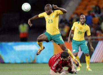El internacional español Xabi Alonso cae al suelo en su lucha por el balón con el sudafricano Tokelo Rantie durante el partido amistoso entre Sudáfrica y España en el estadio Soccer City de Soweto.