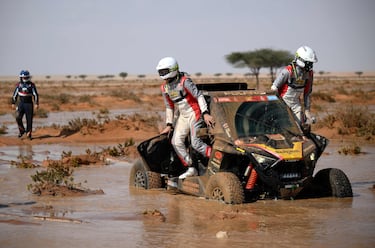 El piloto francés Florent Vayssade (derecha) y su copiloto Nicolas Rey (izquierda) salen de su vehículo después de que se atascara en el barro durante la etapa de hoy. 