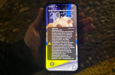 Un vecino sostiene un teléfono móvil que muestra una alerta de emergencia de Protección Civil de España, enviada a los residentes de Ronda, que anuncia una alerta roja meteorológica debido a un riesgo extraordinario de lluvia.