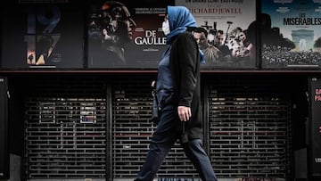 A woman walks past a closed cinema in Paris on April 20, 2020.