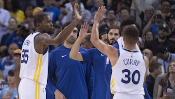 Kevin Durant y Stephen Curry se saludan con el banquillo de los Warriors.