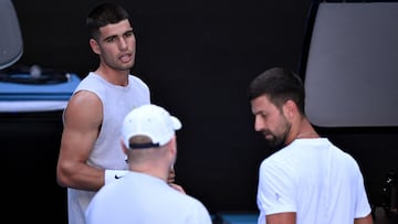 Spain's Carlos Alcaraz (L) chats with Novak Djokovic of Serbia (R) during a training session ahead of the Australian Open tennis tournament in Melbourne on January 7, 2025. (Photo by William WEST / AFP) / --IMAGE RESTRICTED TO EDITORIAL USE - STRICTLY NO COMMERCIAL USE--