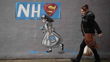 A pedestrian walks past NHS inspired graffiti in England