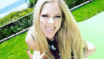 La cantante Avril Lavigne haciendo el símbolo rockero de los cuernos y sacando la lengua en la miniramp de skate de su casa, con la playa y olas al fondo.