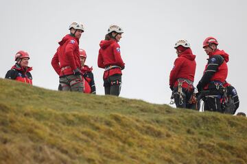 Los príncipes de Gales vestidos con ropa deportiva atienden las explicaciones del grupo de rescate galés. 