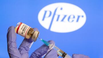 Una mujer sostiene una peque&ntilde;a botella con una etiqueta de &quot;Vacuna contra el coronavirus COVID-19&quot; y una jeringa m&eacute;dica frente al logotipo de Pfizer que se muestra en esta ilustraci&oacute;n tomada el 30 de octubre de 2020. 