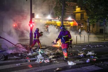 Los bomberos franceses extinguen un incendio en la calle mientras estallan enfrentamientos entre la policía francesa y los aficionados del PSG que celebran la victoria de su equipo en la final de la UEFA Champions League.