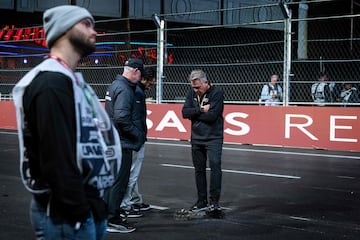 Los funcionarios de operaciones de carrera inspeccionan una tapa de alcantarillado suelta en la pista durante la primera sesión de práctica para el Gran Premio.