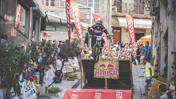 Un ciclista realiza el último salto del MTB Downtown de la ciudad de Vigo (Pontevedra, Galicia) sobre una rampa de Red Bull y Specialied y gente de público a cada lado.