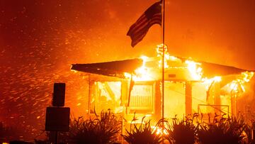 A U.S flag flies as fire engulfs a structure while the Palisades Fire burns during a windstorm on the west side of Los Angeles, California, U.S. January 7, 2025. REUTERS/Ringo Chiu TPX IMAGES OF THE DAY