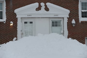 La nieve se acumula alrededor de las puertas de entrada de las casas después de que cayeran más de 60 centímetros de nieve intensa en Derby, Nueva York.