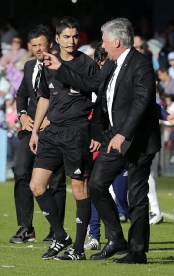 El entrenador italiano del Real Madrid, Carlos Ancelotti (d), habla con el cuarto árbitro en presencia de Luis Enrique (i), técnico del Celta.