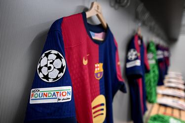 Detalle del escudo de la Fundación UEFA para la Infancia, exhibido en una camiseta de partido dentro del vestuario del FC Barcelona antes del partido de vuelta de cuartos de final de la UEFA Champions League 2024/25.