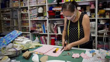 Imagen de una dueña de una mercería recortando tela para realizar una mascarilla.