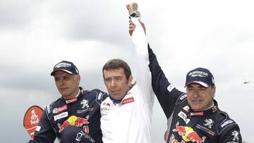 Bruno Famin alza los brazos de Sainz y Cruz, los dos espa&ntilde;oles que han ganado el Dakar.