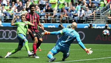 Seattle Sounders forward Raul Ruidiaz, left, scores on Atlanta goal keeper Brad Guzan, right, during the second half of an MLS soccer match Sunday, July 14, 2019, in Seattle. (Ken Lambert/The Seattle Times via AP)