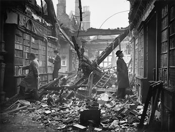 Varios hombres buscan libros en la biblioteca Holland House en Kensington (Londres). Esta biblioteca sufrió un intenso bombardeo que dañó gravemente toda la mansión.