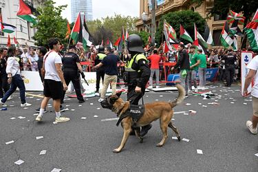 Un agente de policía con un perro pasea ante los manifestantes propalestinos en Bilbao. 