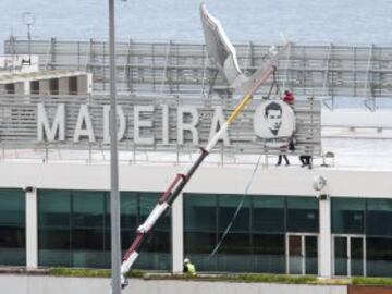 Workers add a sign bearing Cristiano Ronaldo's face to the airport exterior ahead of its 29 March name change to Madeira Cristiano Ronaldo Airport.