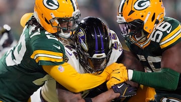 GREEN BAY, WISCONSIN - DECEMBER 27: Derrick Henry #22 of the Baltimore Ravens runs with the ball while being tackled by Xavier McKinney #29 and Edgerrin Cooper #56 of the Green Bay Packers in the second quarter at Lambeau Field on December 27, 2025 in Green Bay, Wisconsin. Patrick McDermott/Getty Images/AFP (Photo by Patrick McDermott / GETTY IMAGES NORTH AMERICA / Getty Images via AFP)