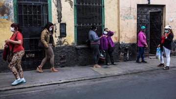 Sex workers on the street wait wearing face masks outside a house where members of the Miluska Life and Dignity Association, a local umbrella group caring for sex workers distribute daily meals from a communal kitchen in downton Lima, on May 28, 2020. - W