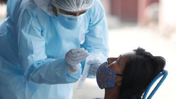 A healthcare worker wearing personal protective equipment (PPE) takes a swab sample from a woman for the coronavirus disease (COVID-19) in Cantagallo, an indigenous Shipibo-Conibo community, during the vaccination campaign against the coronavirus, in Lima, Peru February 19, 2021. REUTERS/Angela Ponce