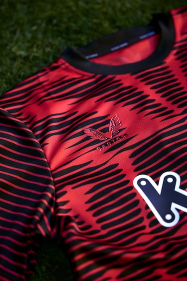 El cuello es redondo de color negro, y el escudo es duotono (rojo y negro) con un brillo imponente.