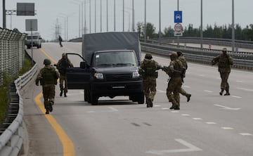 Los combatientes del grupo de mercenarios privados de Wagner caminan alrededor de un vehículo durante una parada en la autopista M-4, que une la capital Moscú con las ciudades del sur de Rusia.
