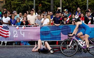 Entr¨® en escena el triatl¨®n ol¨ªmpico, que finalmente pudo disputarse en sus tres disciplinas: nataci¨®n en el Sena, ciclismo y carrera pedestre. En la imagen, la italiana Verena Steinhauser pasa en bicicleta por el Puente Alejandro III de Par¨ªs, a la altura de una atleta tumbada sobre el suelo adoquinado tras una ca¨ªda que estremeci¨® al p¨²blico.