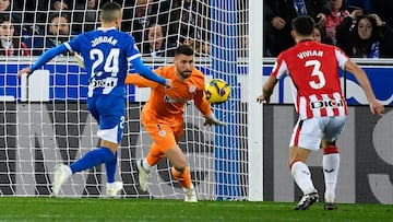 Alaves' Spanish midfielder #24 Joan Jordan Moreno (L) goes for a loose ball before scoring as Athletic Bilbao's Spanish goalkeeper #01 Unai Simon fails to stop the ball during the Spanish league football match between Deportivo Alaves and Athletic Club Bilbao at the Mendizorroza stadium in Vitoria on December 15 , 2024. (Photo by ANDER GILLENEA / AFP)