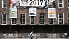 Una mujer rueda en bicicleta por las calles de Dusseldorf ante un cartel promocional del Tour de Francia.