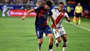 El centrocampista del Huesca Gonzalo Melero (i) y el centrocampista argentino del Rayo Vallecano Oscar Guido luchan por el balón durante el partido de la cuarta jornada que disputan en el campo de fútbol El Alcoraz.
