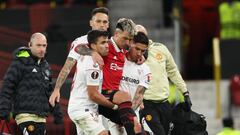 MANCHESTER, ENGLAND - APRIL 13: Marcos Acuna of Sevilla and Gonzalo Montiel of Sevilla carry off Lisandro Martinez of Manchester United after an injury during the UEFA Europa League quarterfinal first leg match between Manchester United and Sevilla FC at Old Trafford on April 13, 2023 in Manchester, United Kingdom. (Photo by Matthew Ashton - AMA/Getty Images)