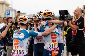 Los ciclistas del equipo dsm-Firmenich PostNL, celebran el doblete en la primera etapa, con  Romain Bardet y Frank Van Den Broek.

