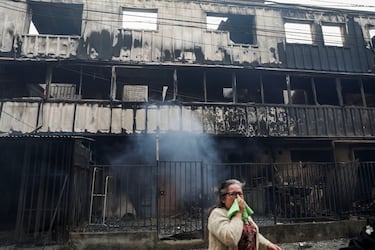 Una persona reacciona frente a un edificio quemado mientras el fuego y el humo se elevan de un incendio forestal en la región del Biobío, donde, según medios locales, múltiples incendios forestales provocaron evacuaciones de emergencia, en Concepción, Chile.