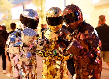 Tres seguidores vestidos con disfraces espectaculares posando antes de la carrera.