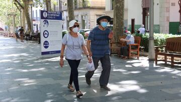 Dues persones amb mascareta passant per davant d&#039;un cartell de recomanacions a la Rambla de Figueres aquest 3 d&#039;agost del 2020. (Horitzontal)