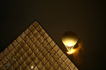 El globo que transporta el pebetero y la llama olímpica se eleva cerca de la Pirámide Invertida del Museo del Louvre.