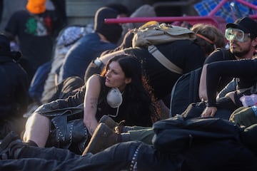 Manifestantes se esconden tras sillas colocadas en la calle para protegerse de los proyectiles "menos letales" disparados por la policía durante una protesta contra las redadas federales de inmigración en el centro de Los Ángeles.