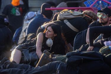 Manifestantes se esconden tras sillas colocadas en la calle para protegerse de los proyectiles "menos letales" disparados por la policía durante una protesta contra las redadas federales de inmigración en el centro de Los Ángeles.