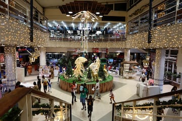 La gente camina en el centro comercial SOCOCE (HYPER U) decorado con iluminacin antes de la celebracin navide?a en Abidjan, Costa de Marfil. 