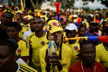 A fan of Colombia holds an image of the virgin Mary during the broadcasting of the Round of 16 World Cup football match between Colombia and England in Yerry Mina's hometown Guachene, in Cauca department, Colombia, on July 3, 2018. / AFP PHOTO / Luis ROBA